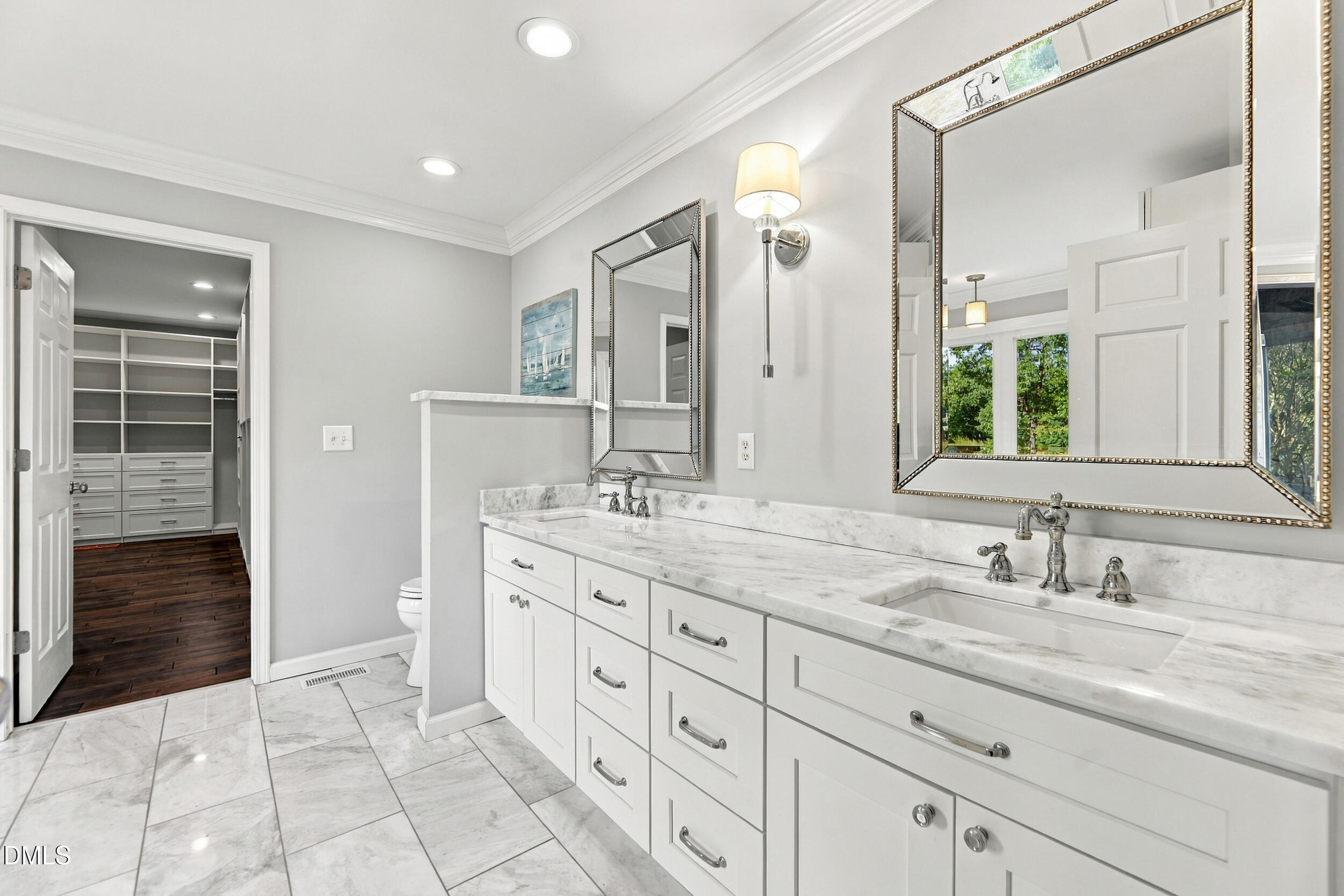 Bathroom with a long marble-topped double vanity and an open doorway to a built-in closet.