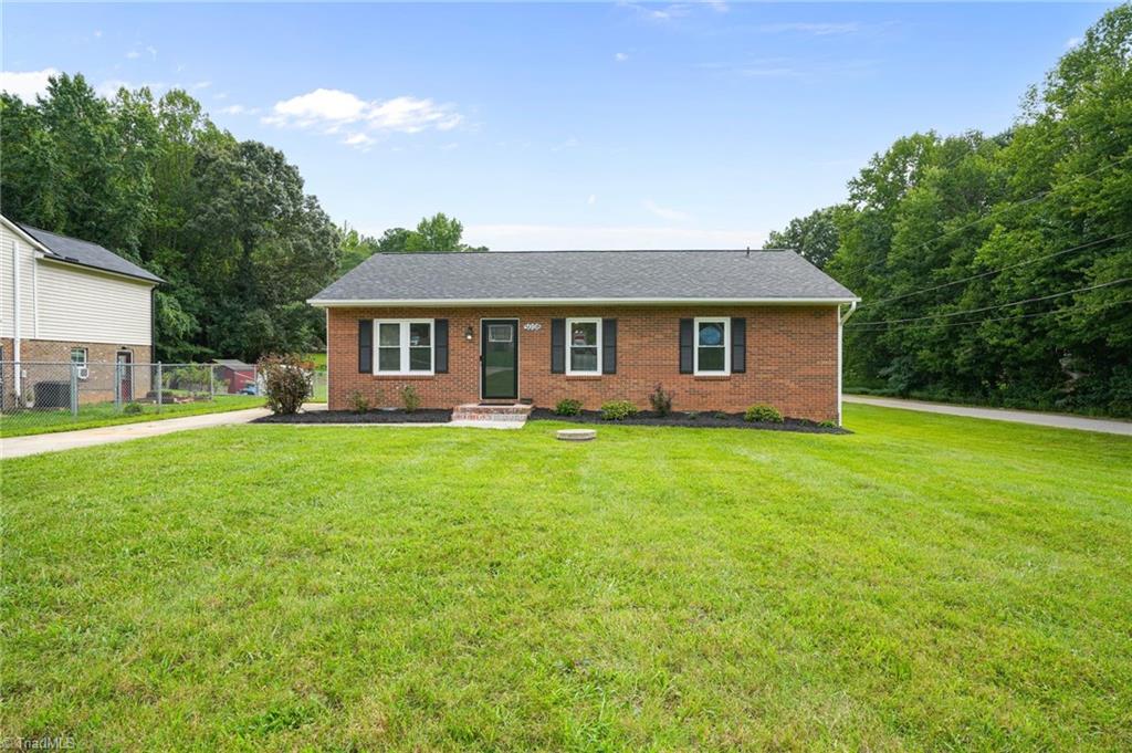 Single-story brick house with dark shutters and a wide front lawn.