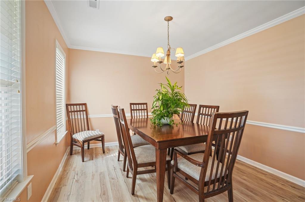 Dining room with a dark wood table, matching chairs, central plant, and chandelier.