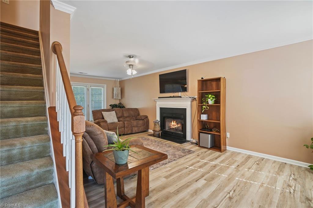 Living room with a lit fireplace, brown sofas, and a carpeted staircase.