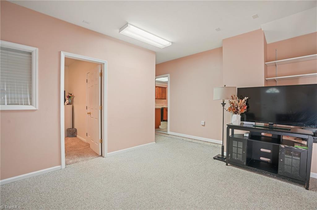 Carpeted living room with a television and media console against pale pink walls.