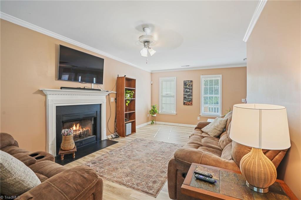 Furnished living room with brown sofas, a lit fireplace, and a wall-mounted television.