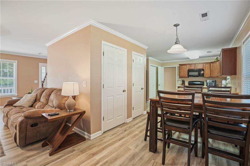 Open-plan living and dining area with brown sofa, dark wood table, and adjoining kitchen.