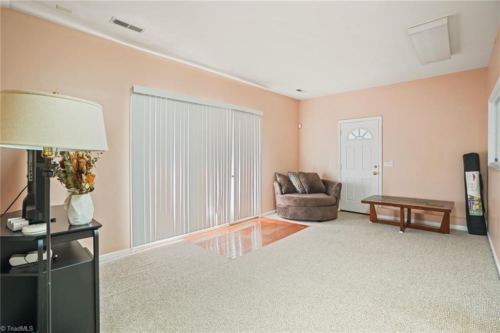Living room with peach walls, carpet, vertical blinds, and a brown loveseat beside a wooden coffee table.