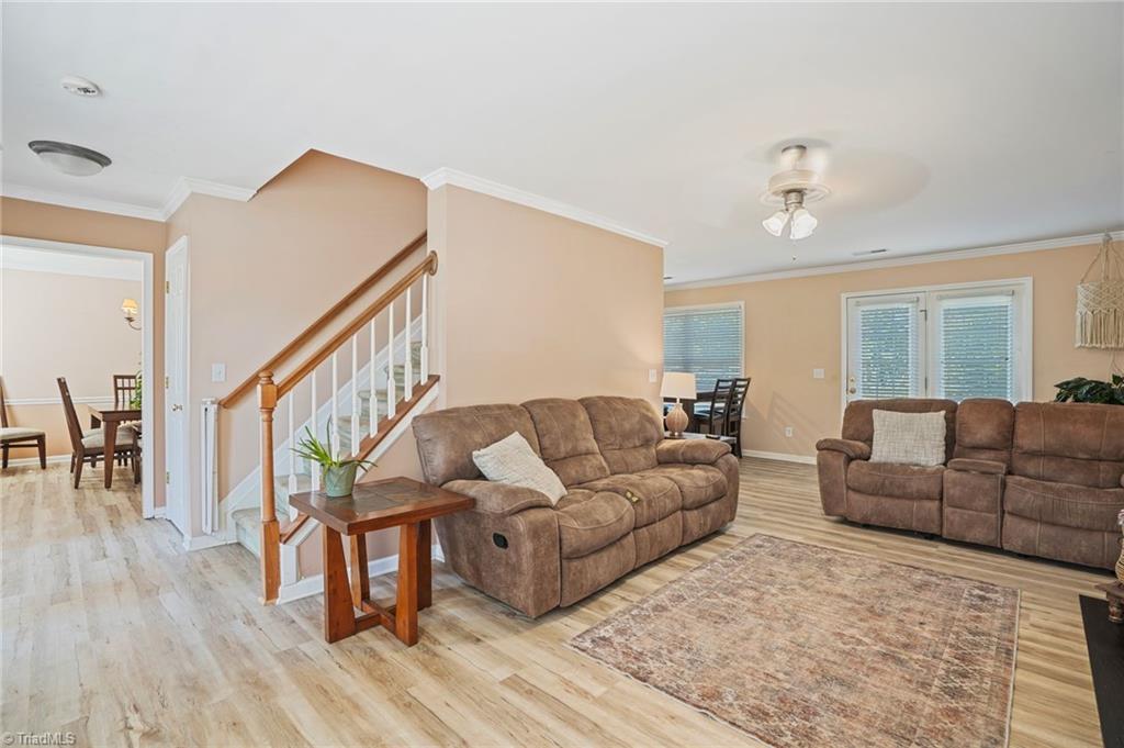 Living room with brown reclining sofas, a patterned rug, and a staircase with a wood handrail.
