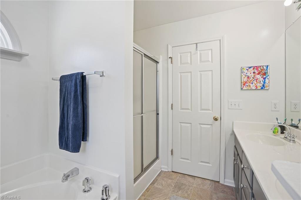 Bathroom with a glass shower, bathtub, and long vanity with dark cabinetry.