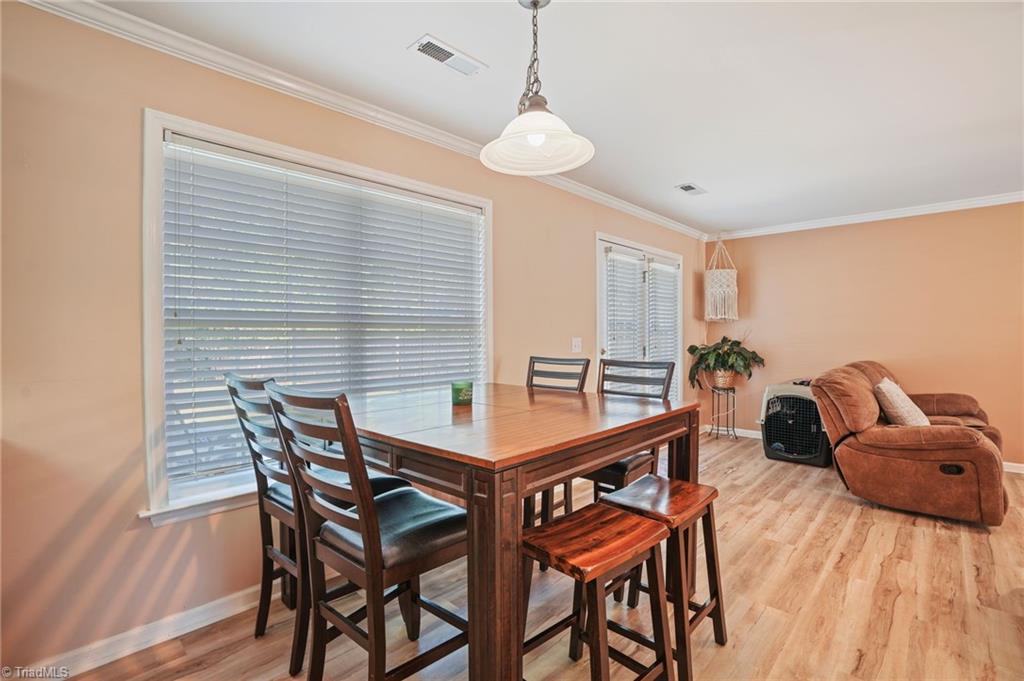 Dining area with a dark wood table, chairs, large blinded windows, and light wood flooring.