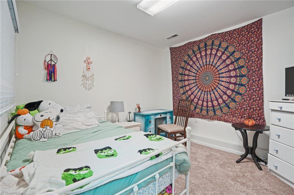Bedroom with aqua bedding, a green patterned quilt, and a colorful mandala tapestry.