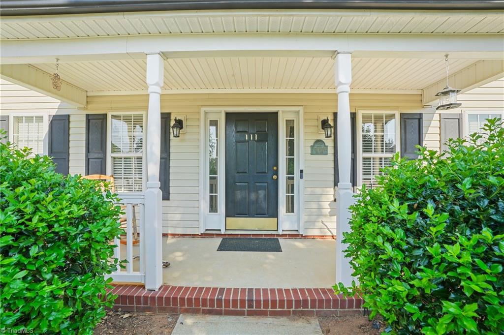 Front entrance with a covered porch, white columns, dark door, and brick steps.