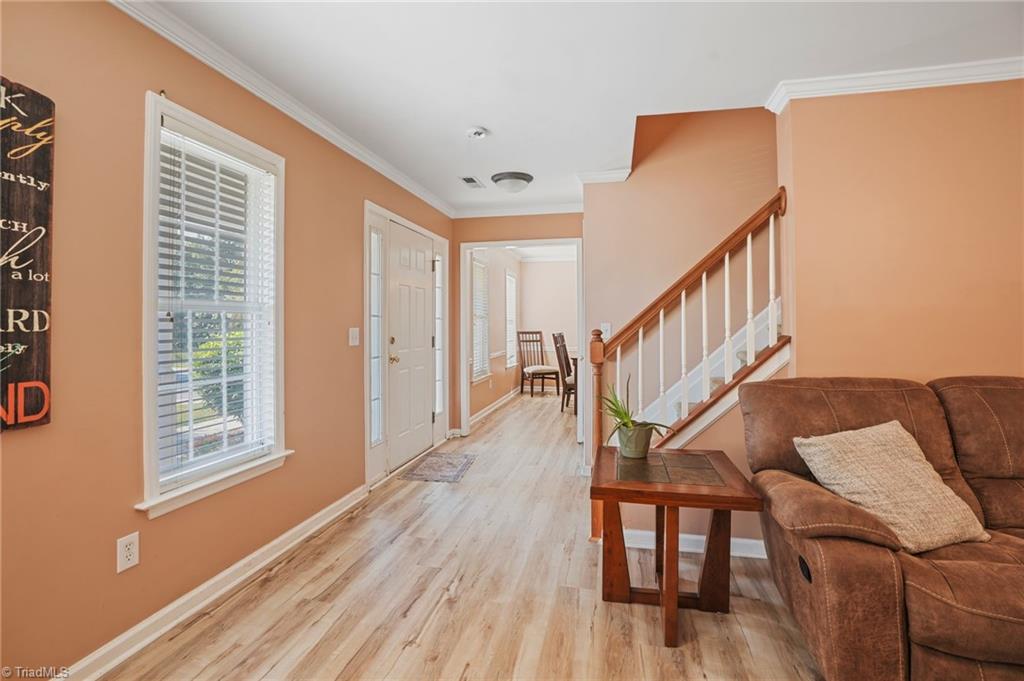Hallway with a staircase, light wood flooring, and a brown sofa beside the entry.