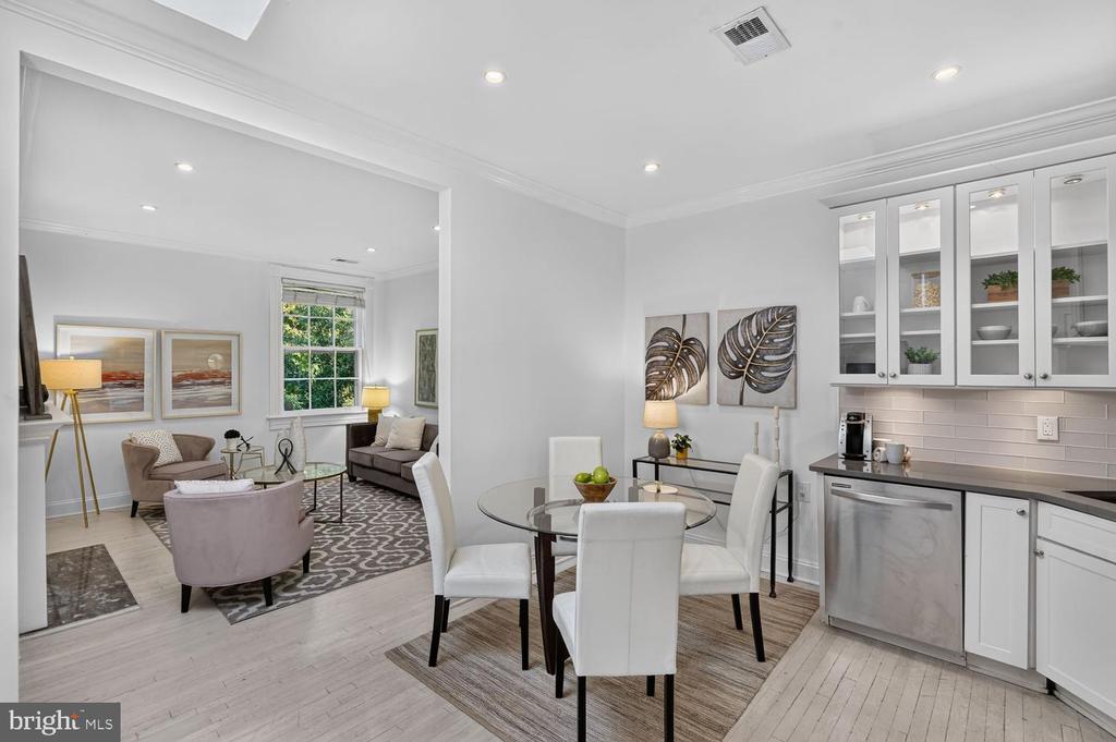 Open-plan condo kitchen and dining area with glass-front cabinets and a glass dining table.