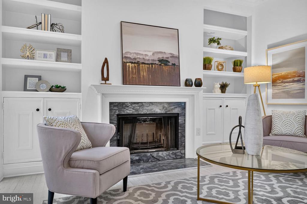 Living room with a marble fireplace, white built-ins, and upholstered seating.