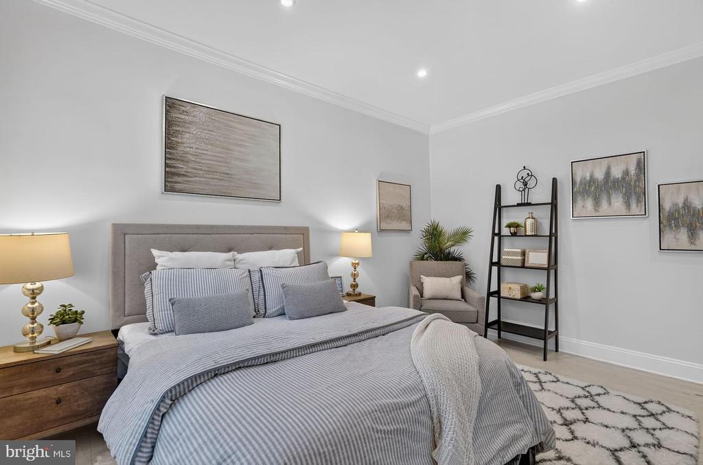 Staged bedroom with a large gray-striped bed, tufted headboard, and ladder shelf.