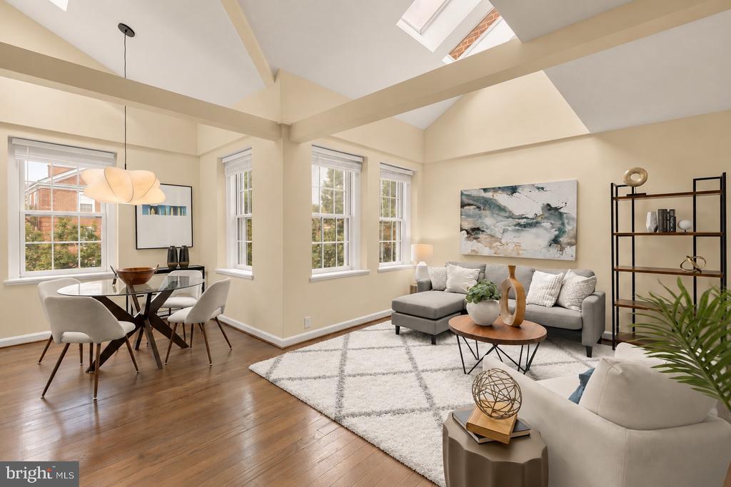 Open-plan living and dining room with vaulted ceilings, skylights, and hardwood floors.