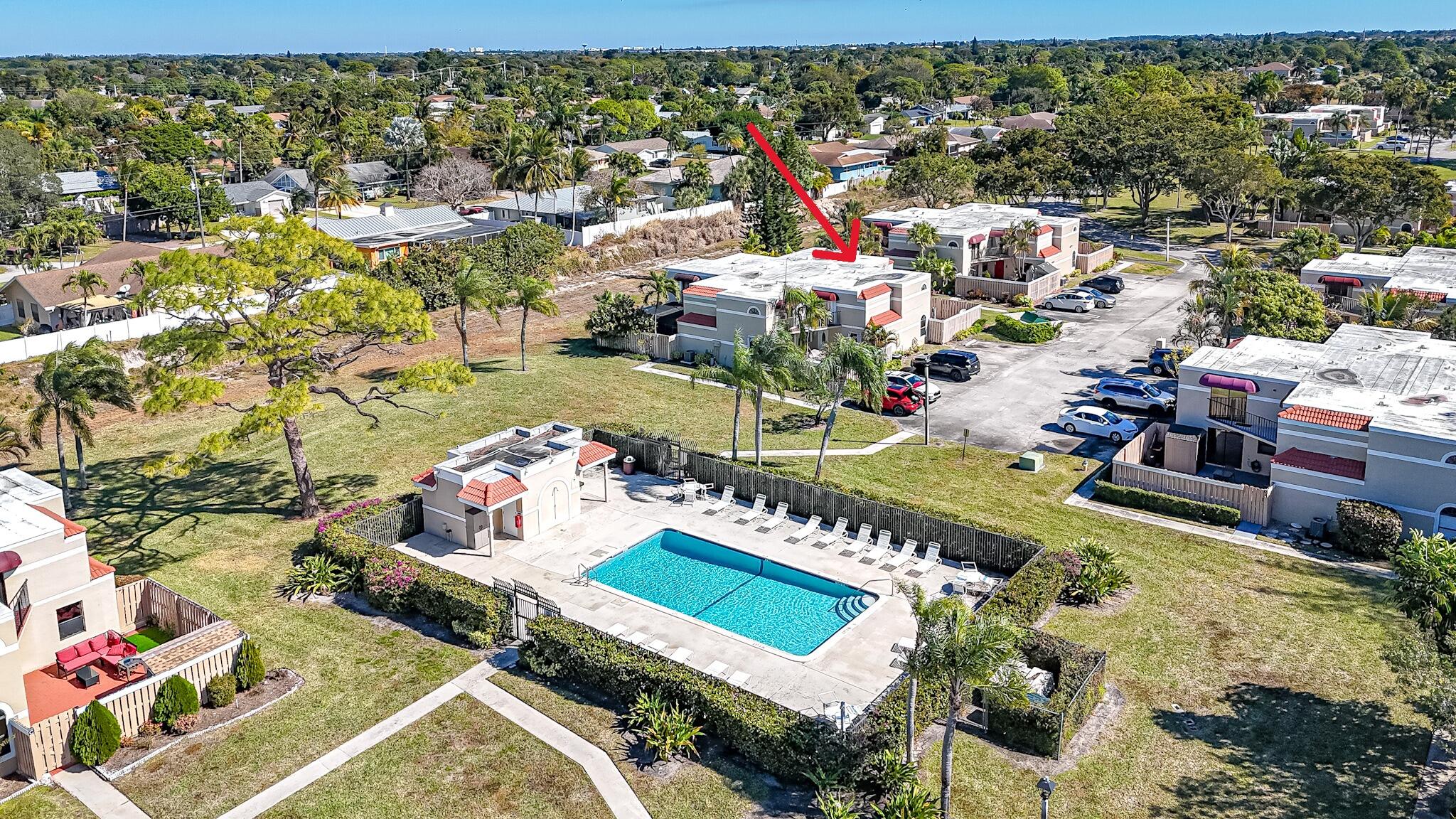 Aerial view of homes and community pool, with a red arrow highlighting one building.