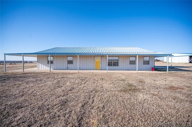 Single-story rural home with a blue metal roof, covered porch, and yellow front door.