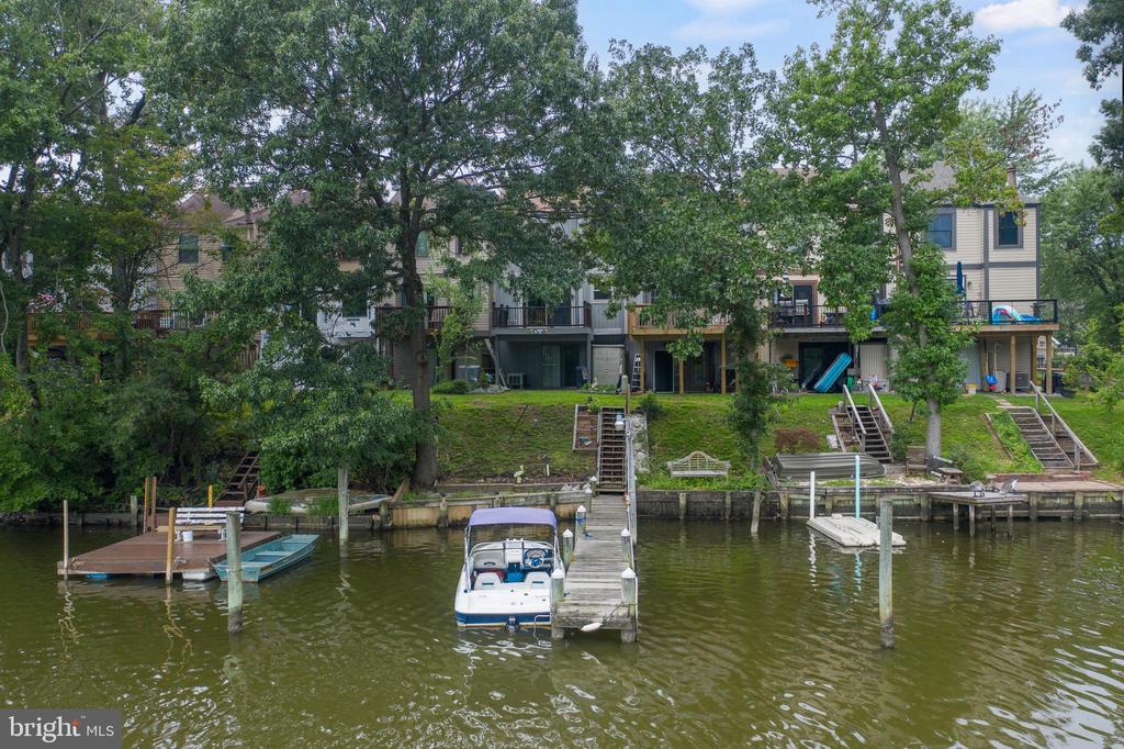 Waterfront townhomes with private docks and boats along a tree-lined shore.