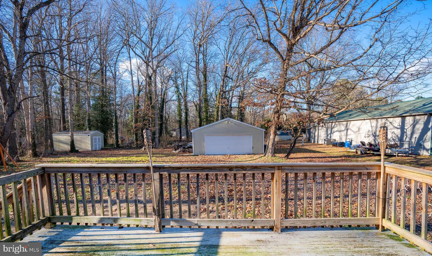 Wooded backyard seen from a raised deck, with a detached garage and storage shed.