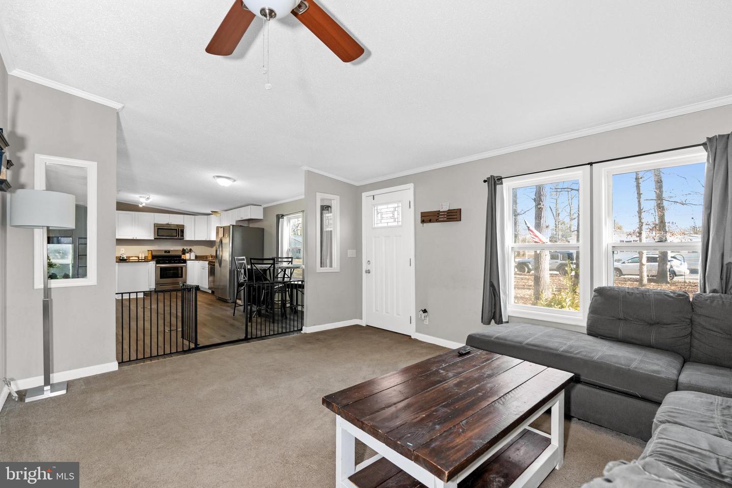 Living room with a gray sectional and dark wood coffee table, open to a kitchen.