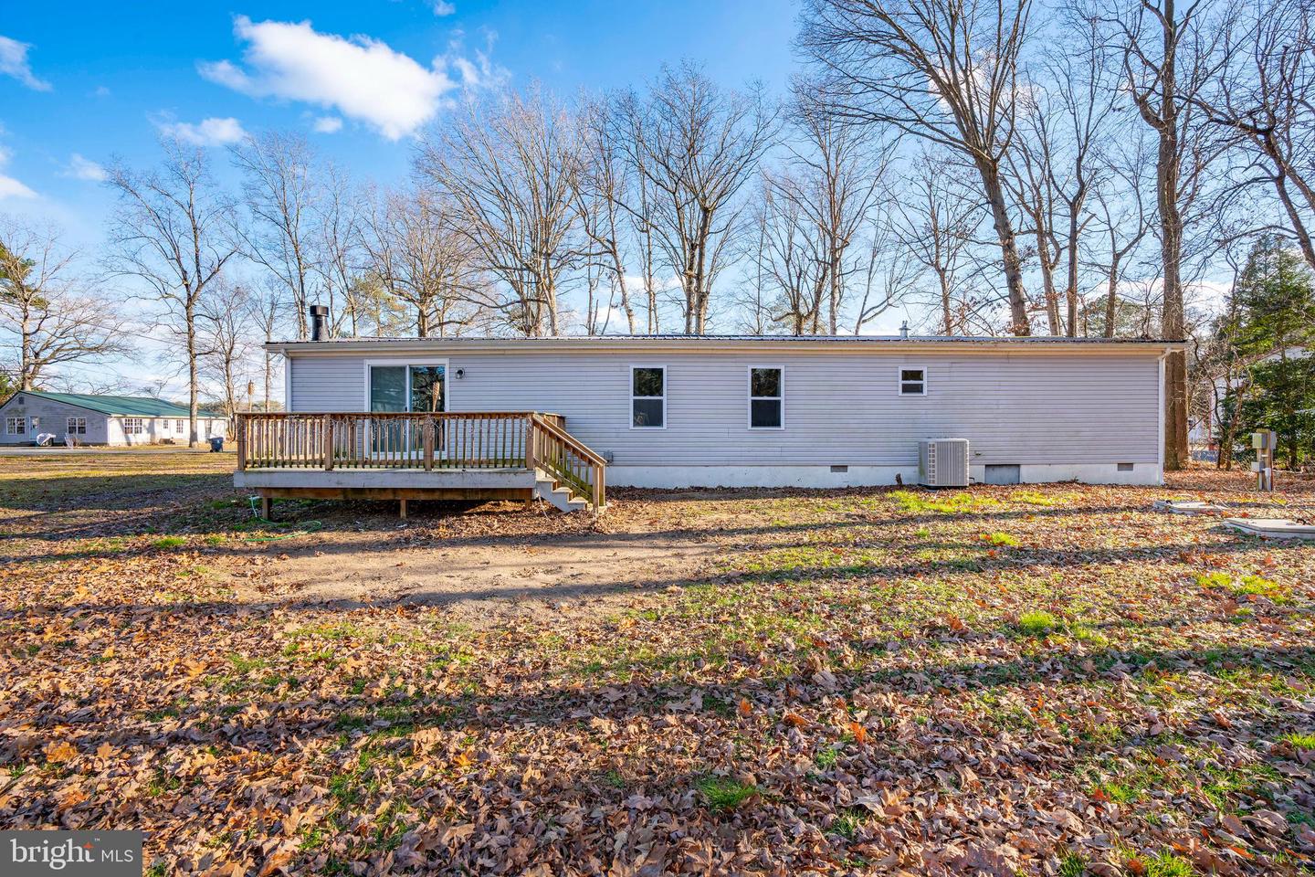 Rear exterior of a single-story home with a raised wooden deck and bare trees.