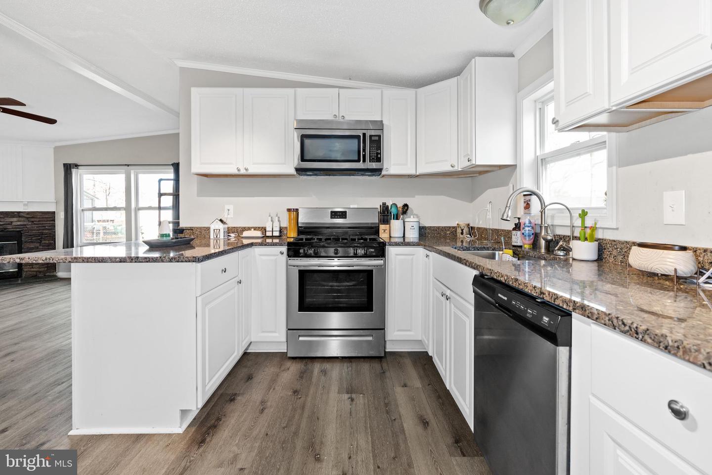Kitchen with white cabinets, granite counters, stainless steel appliances, and a broad peninsula.