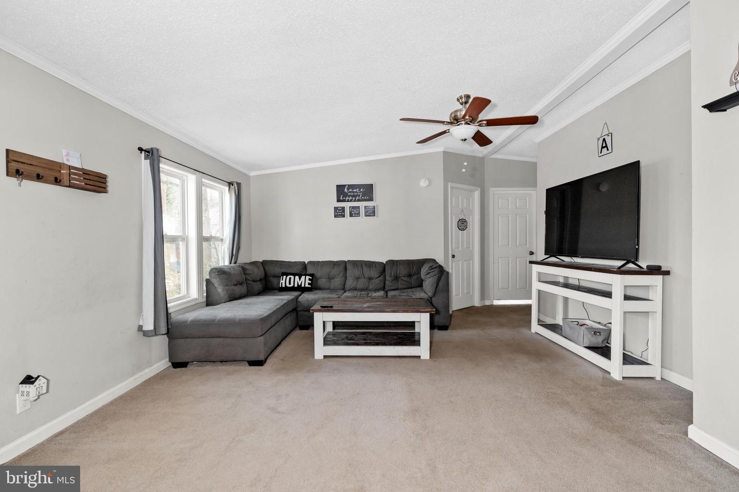 Living room with a gray sectional, white coffee table, and television console.