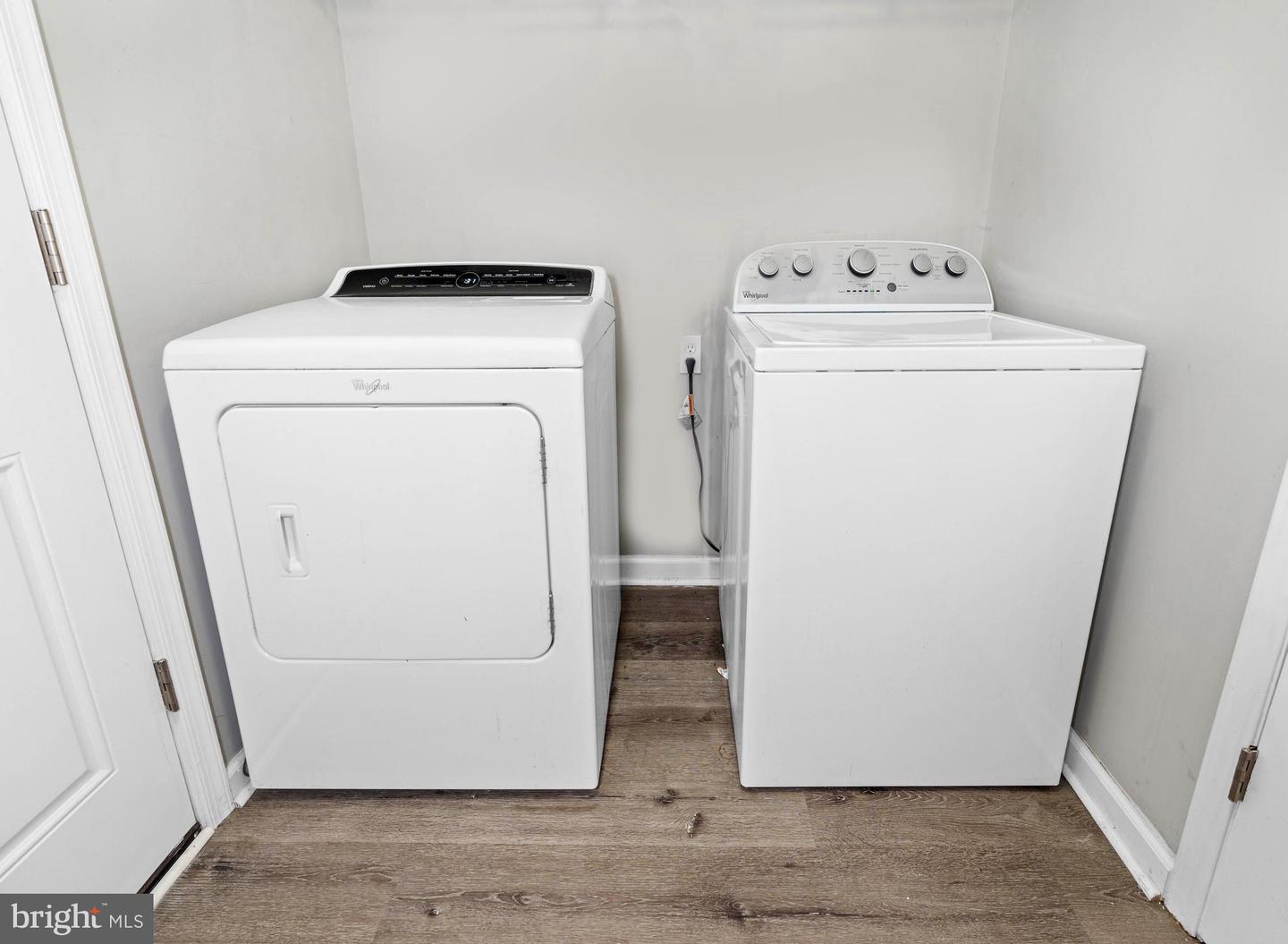 Laundry room with a white washer and dryer and wood-look flooring.