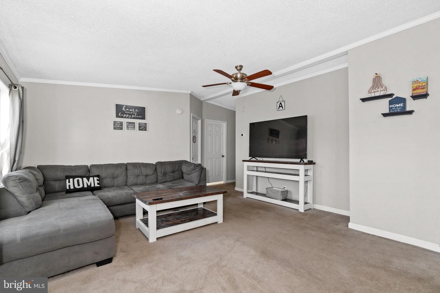 Living room with a gray sectional, wood-top coffee table, and television.