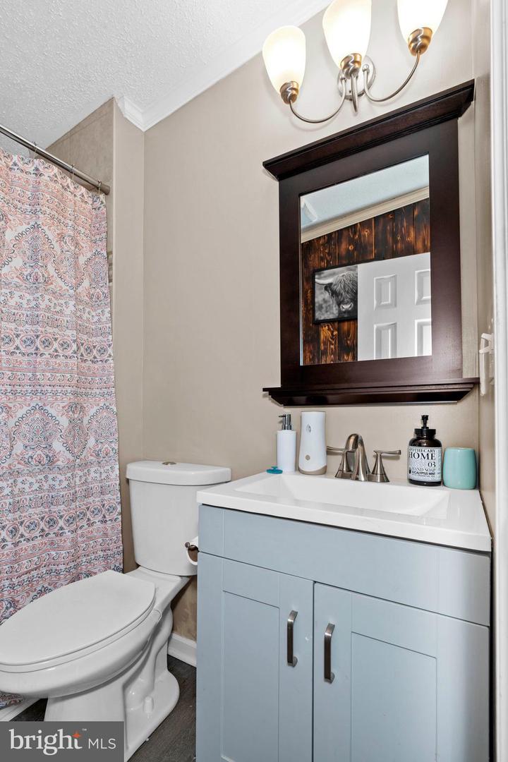 Bathroom with a light blue vanity, dark-framed mirror, and patterned shower curtain.
