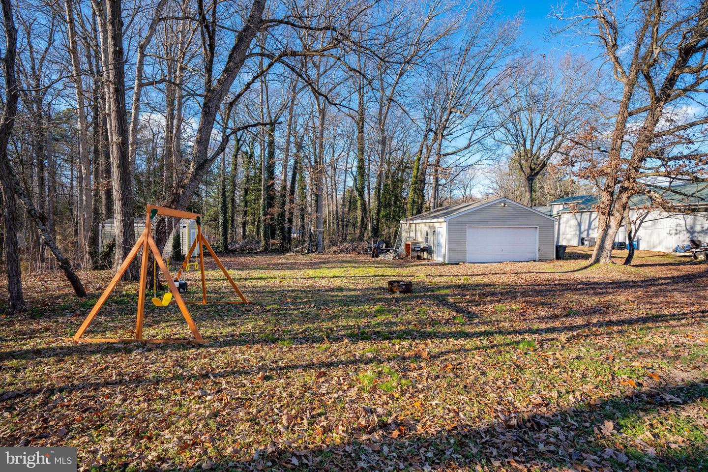 Wooded backyard with a swing set and detached garage.