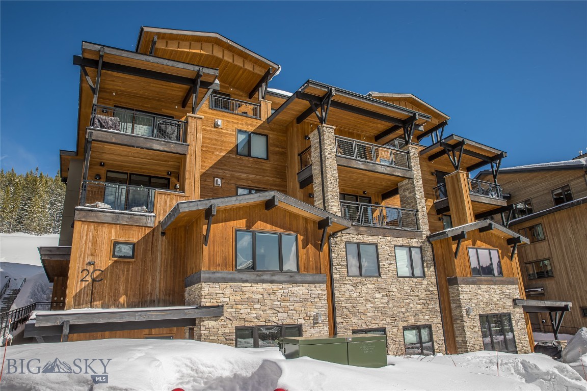 Snowy mountain residence with wood-and-stone facade, balconies, and a visible 2C marking.