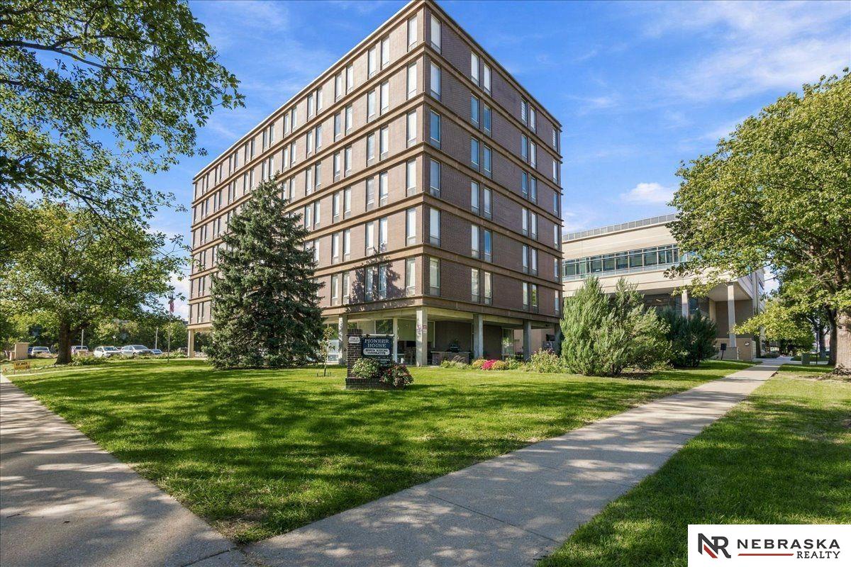 Multi-story office building beside a landscaped lawn and mature trees.