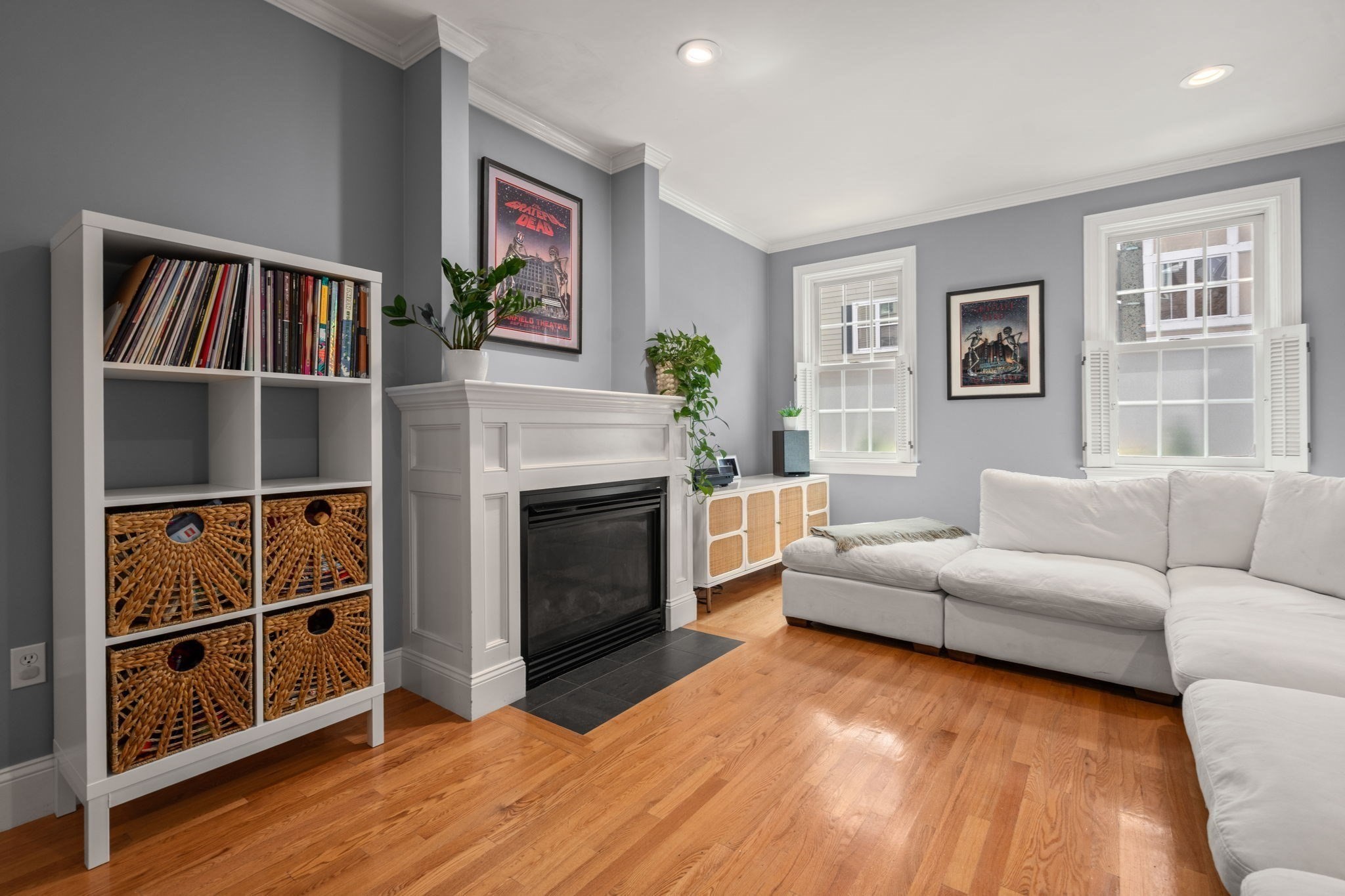 Living room with a white fireplace, sectional sofa, and hardwood floors.