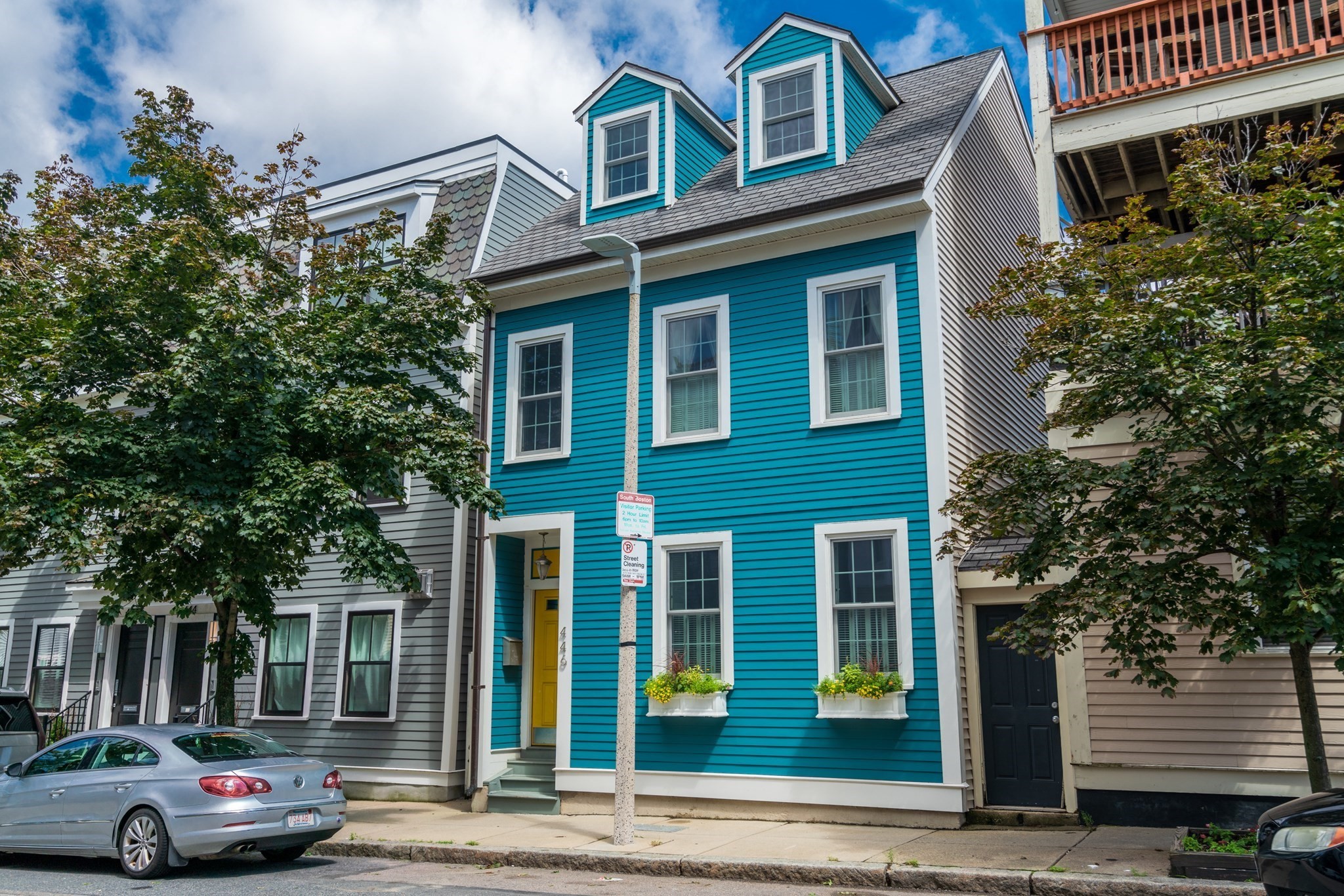 Turquoise South Boston townhouse with twin roof dormers, white trim, and a yellow front door.