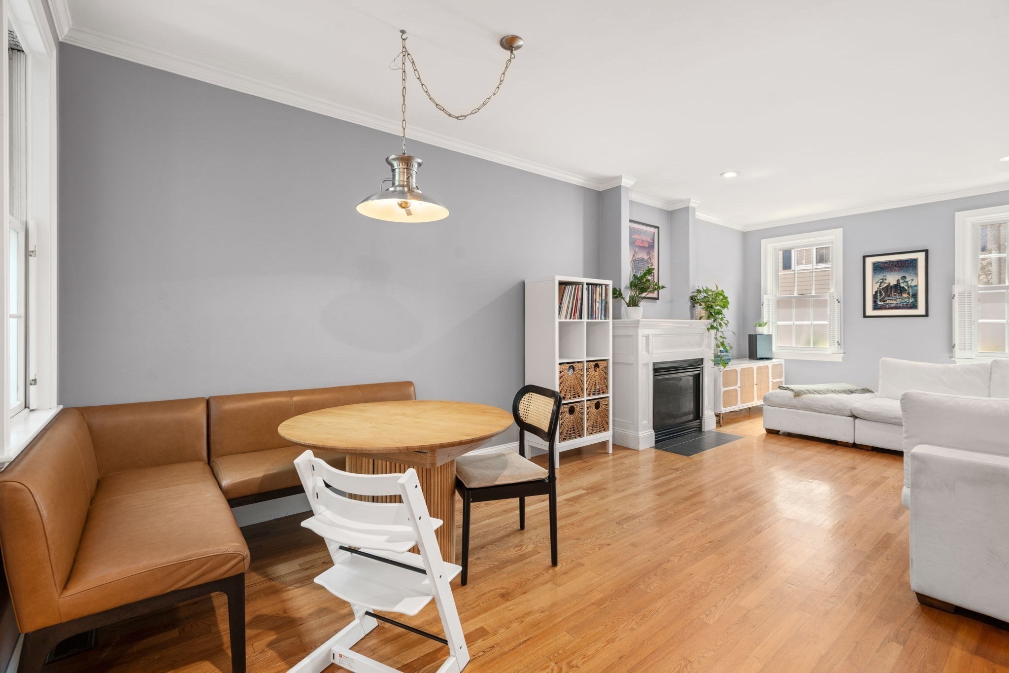 Open living and dining room with a leather banquette, round wood table, hardwood floors, and fireplace.