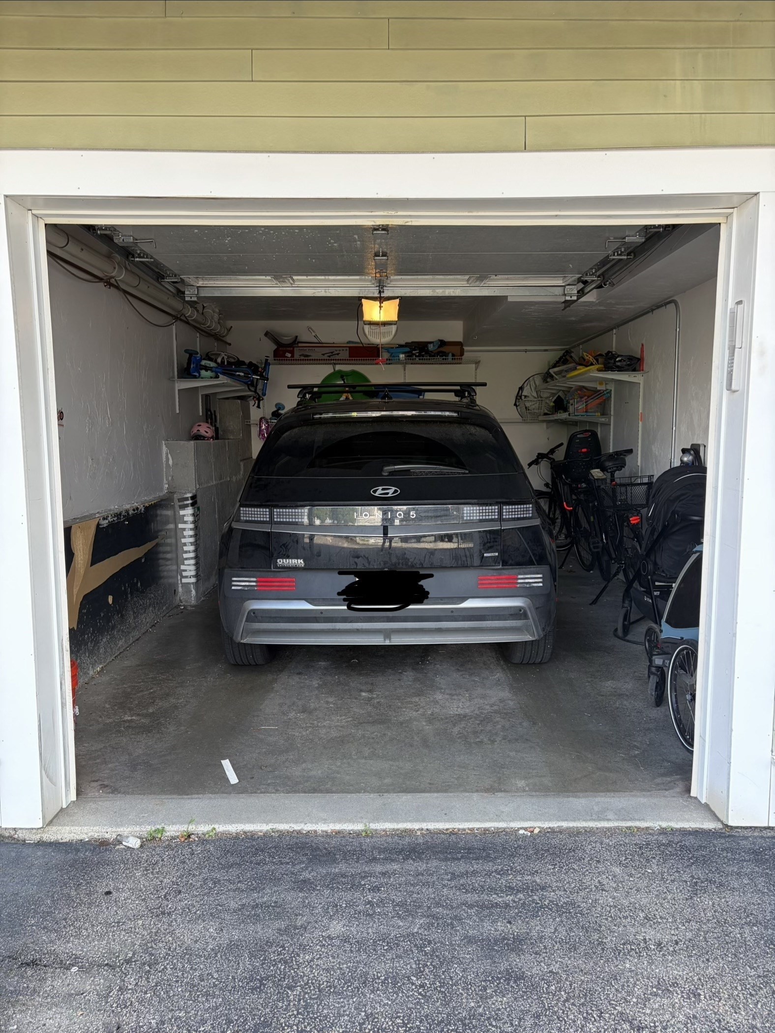 Garage with a gray Hyundai, bicycles, stroller, and storage shelves.