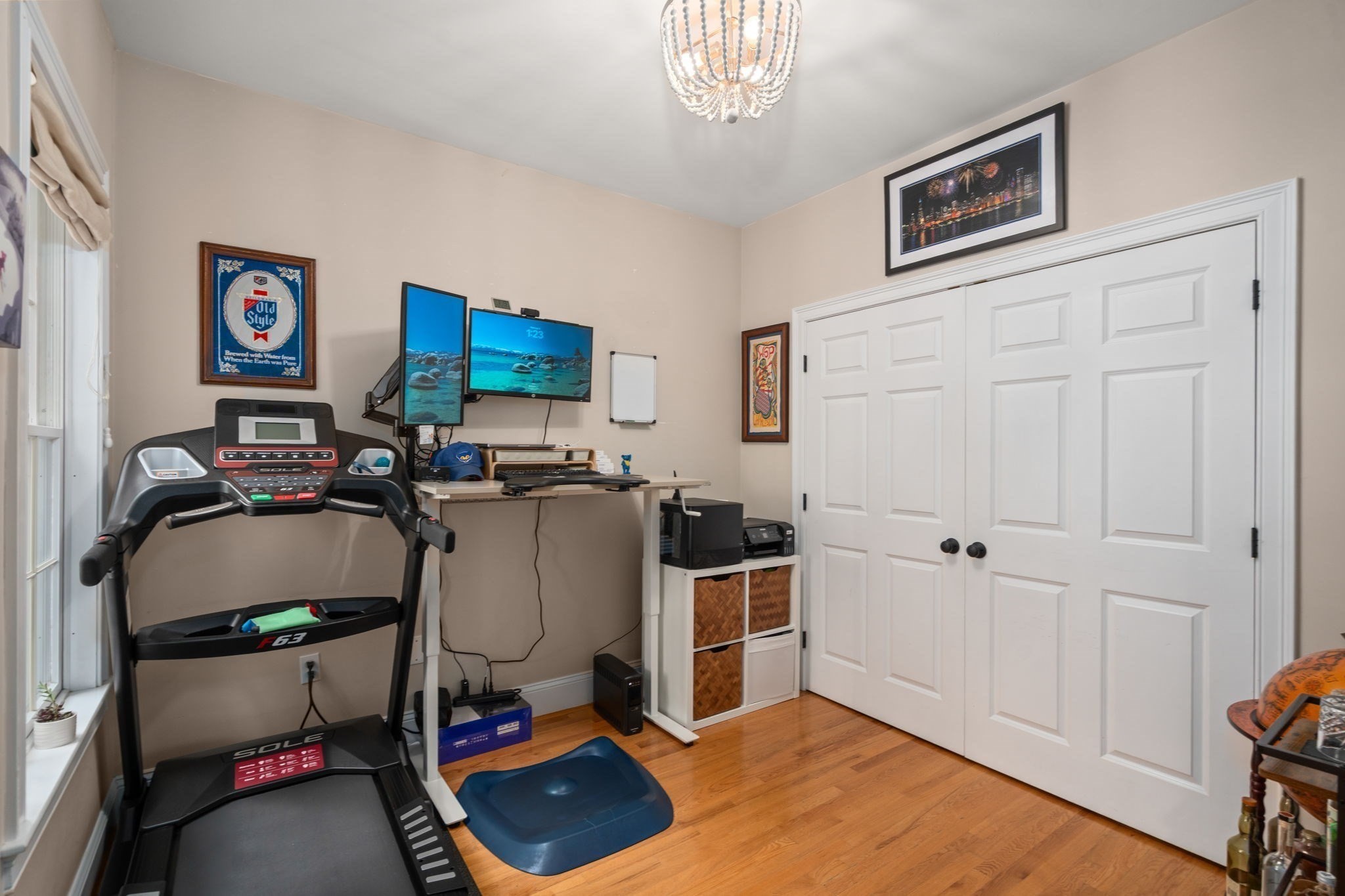 Exercise room with a treadmill, blue mat, workstation, and white double closet doors.