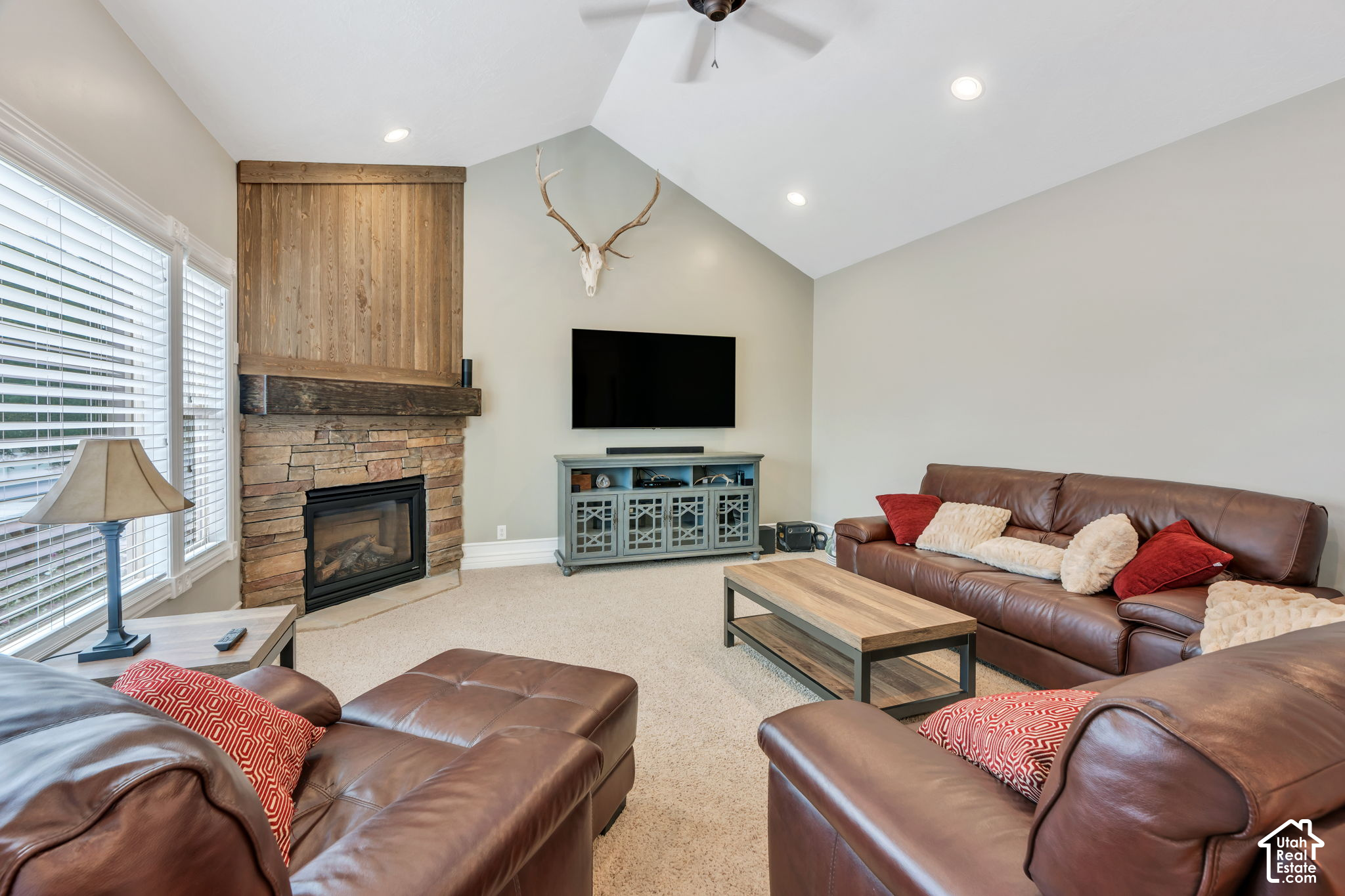 Living room with leather sofas, a stone fireplace, and a vaulted ceiling.