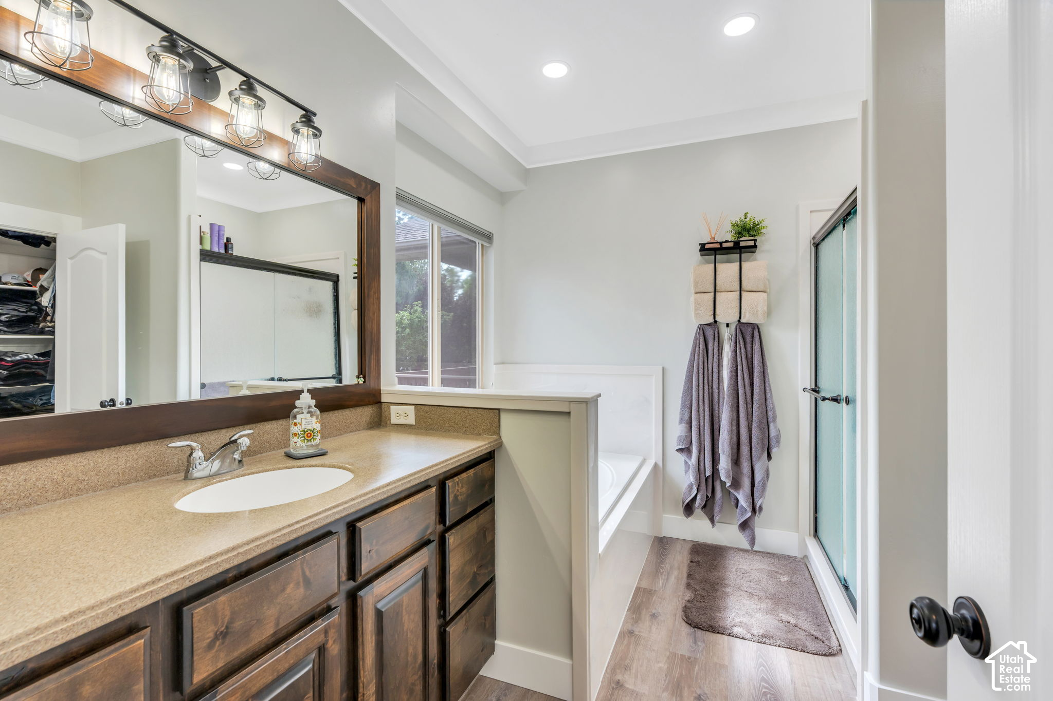Bathroom with dark wood vanity, framed mirror, bathtub, and glass shower door.