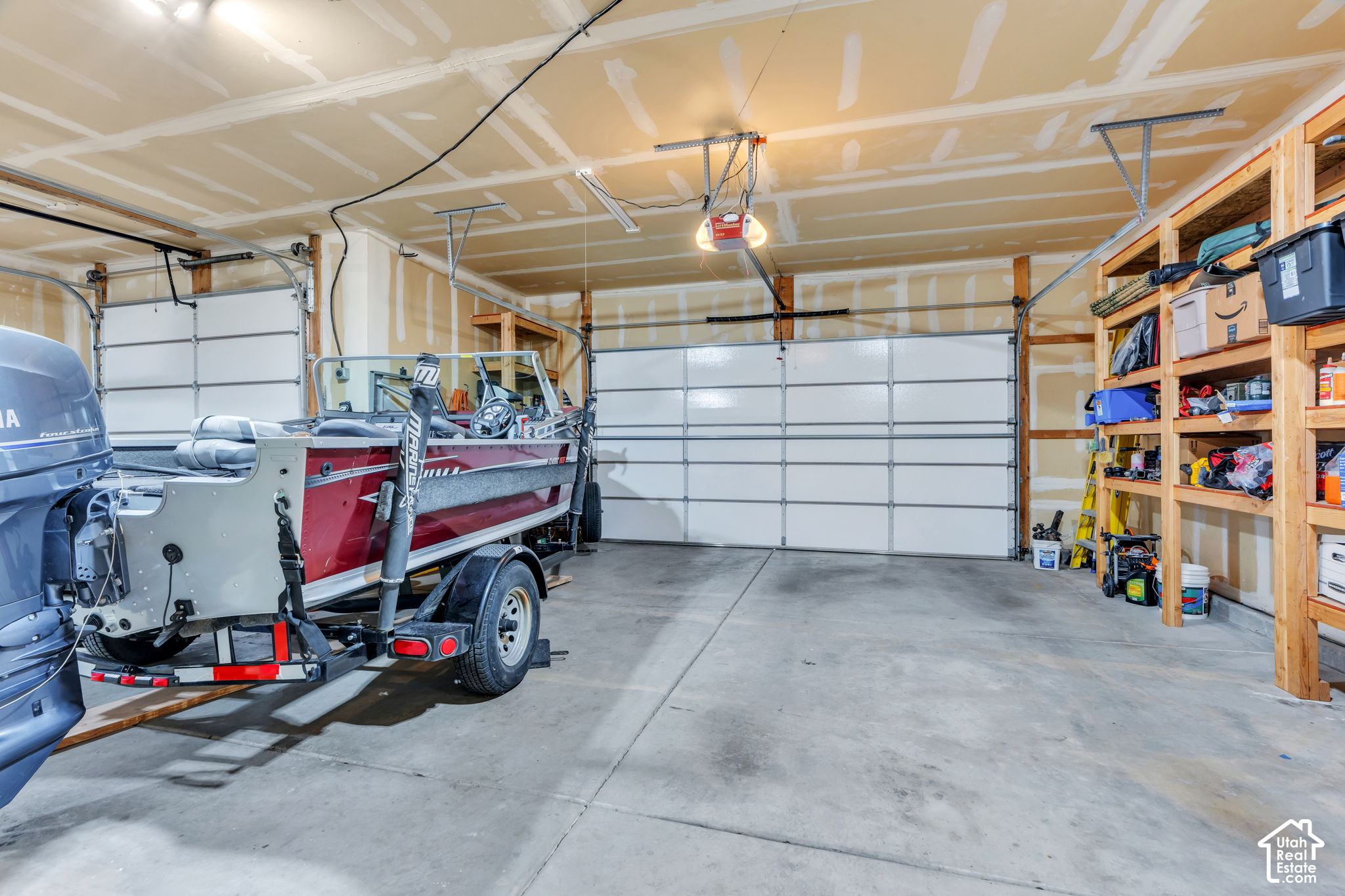 Spacious garage with a red-and-gray boat on a trailer and open storage shelving.