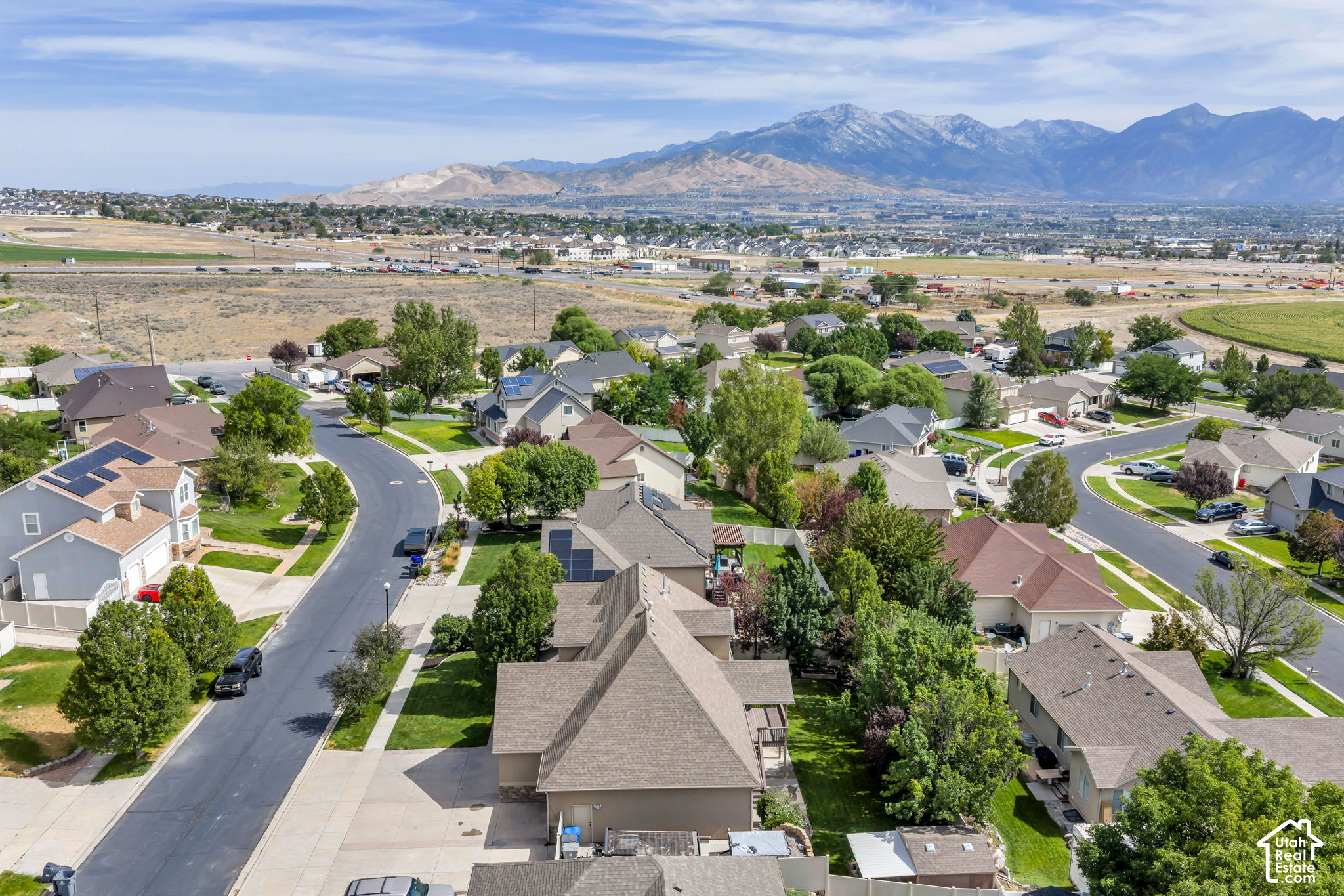 Aerial view of Saratoga Springs homes and curving streets, with the Wasatch Mountains in the distance.