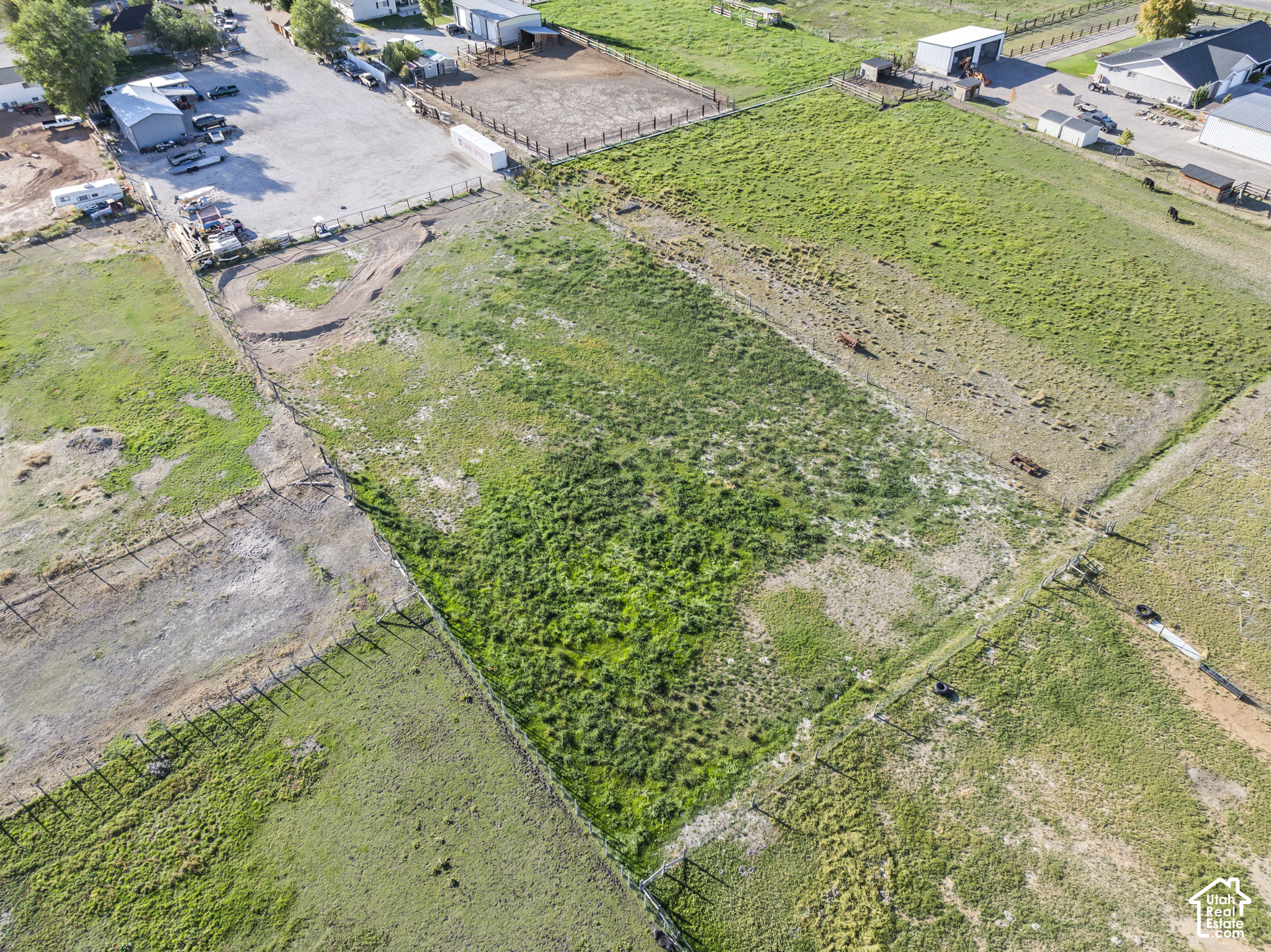 Aerial view of fenced pastureland with farm buildings and grazing animals.