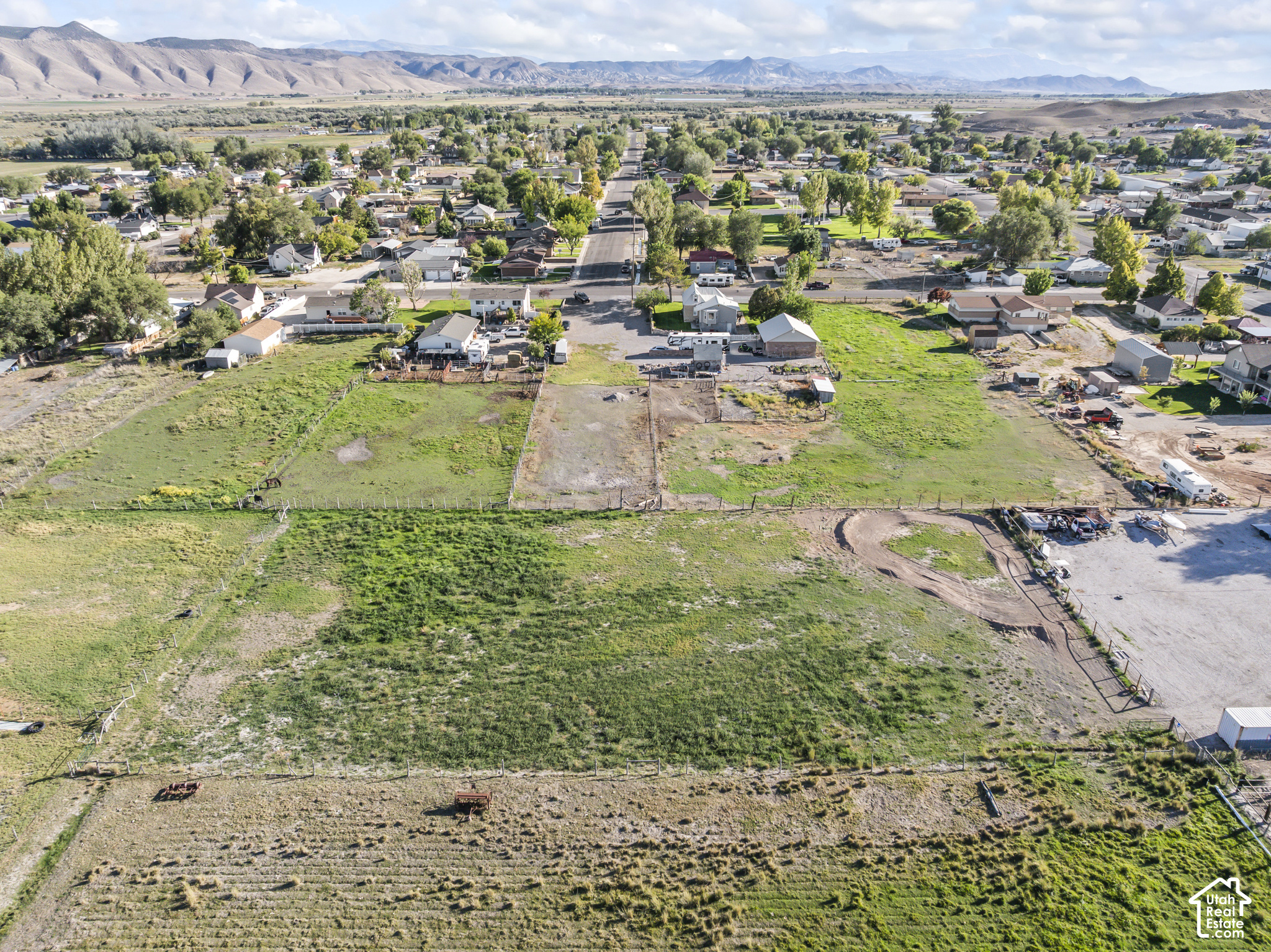 Aerial view of fenced grassy acreage in Redmond, with homes and mountains beyond.