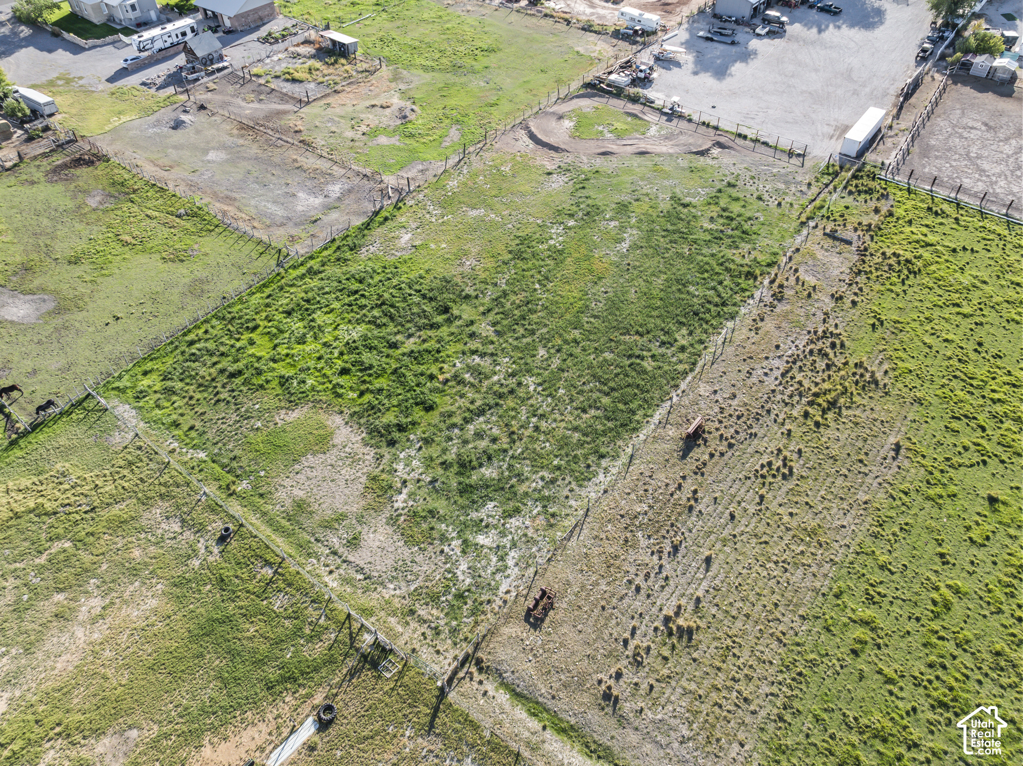 Aerial view of fenced pasture divided into paddocks, with horses near the edge.