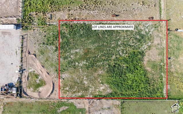 Aerial view of a vacant lot outlined in red, labeled that lot lines are approximate.