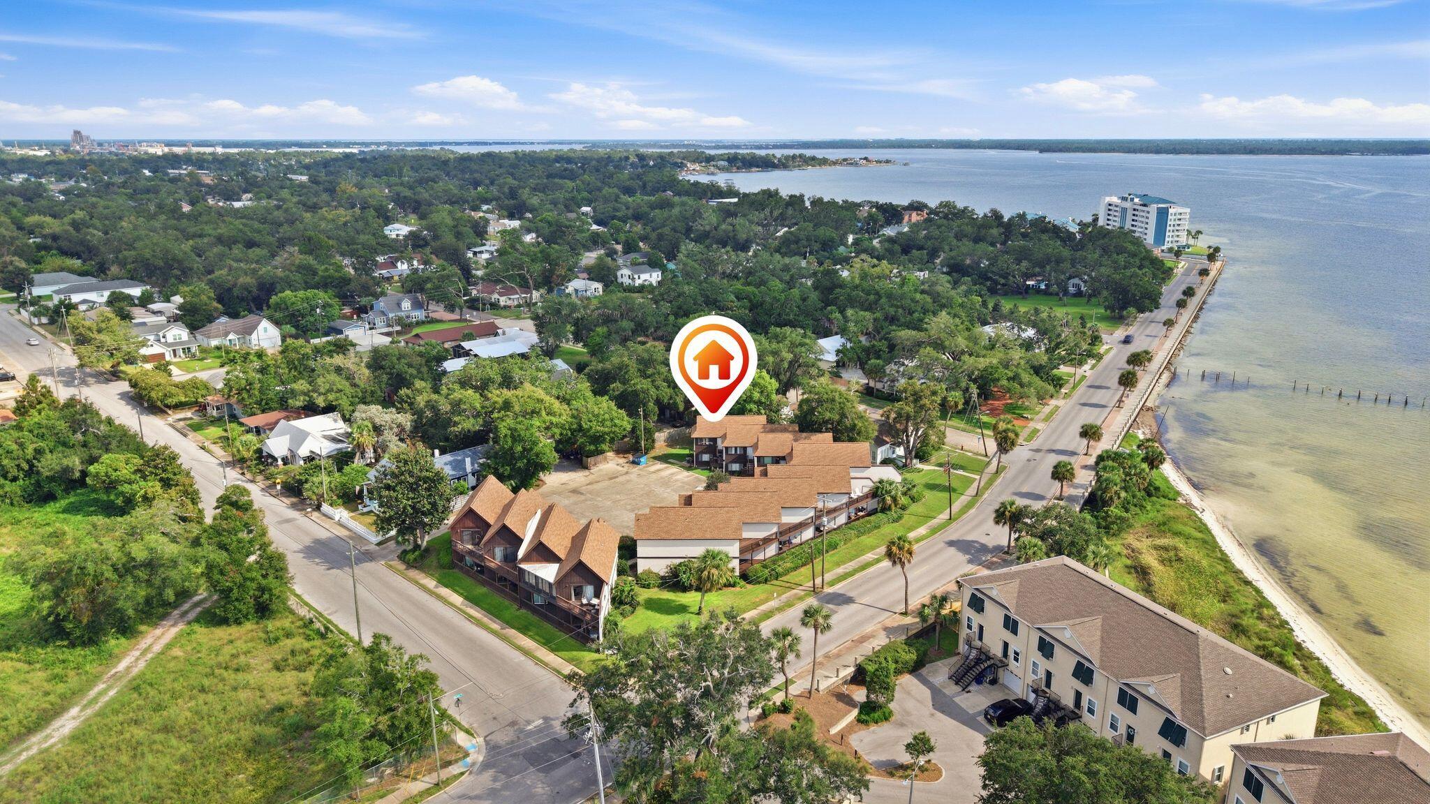 Aerial view of a leafy Panama City neighborhood, with homes beside the bay and a red home-location marker.
