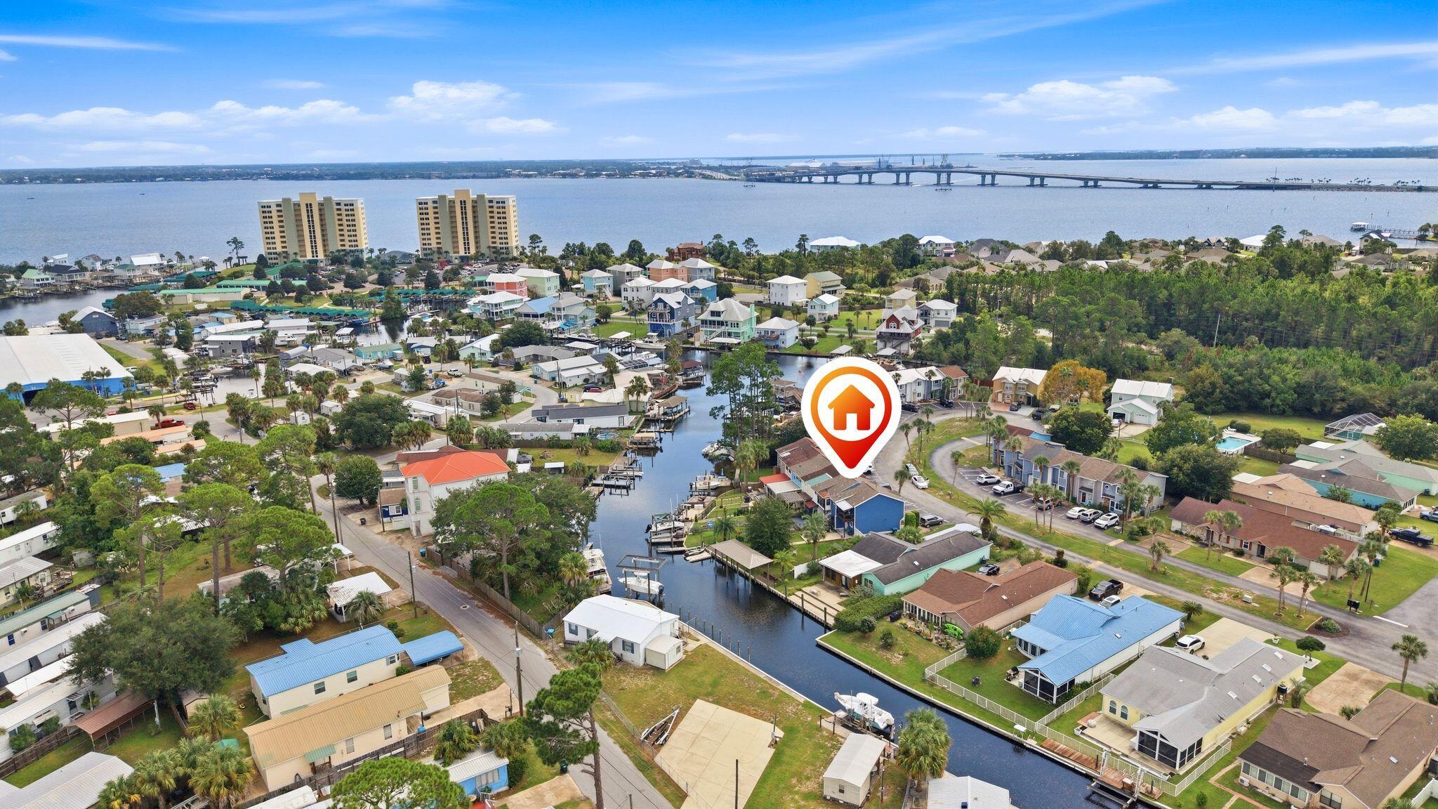 Aerial view of Panama City Beach homes along canals, with a bay and bridge beyond.