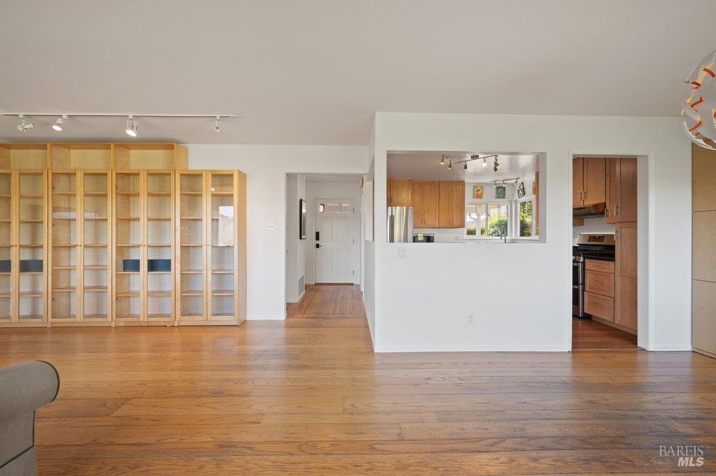 Living room with built-in wood shelving, hardwood floors, and a kitchen pass-through.