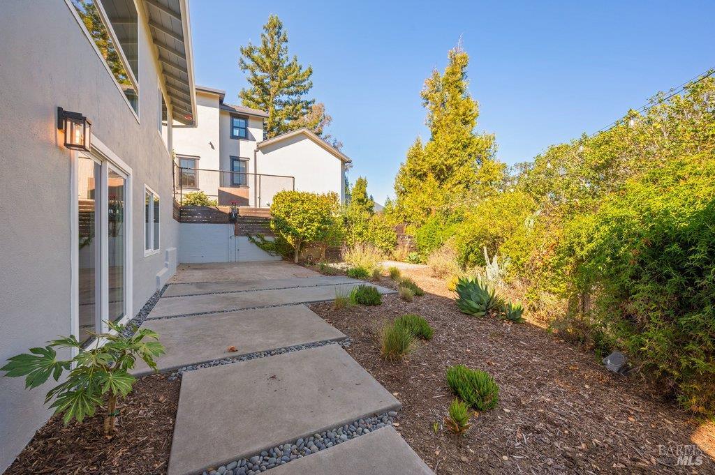 Home’s side patio with a concrete walkway, gravel borders, and landscaped yard.