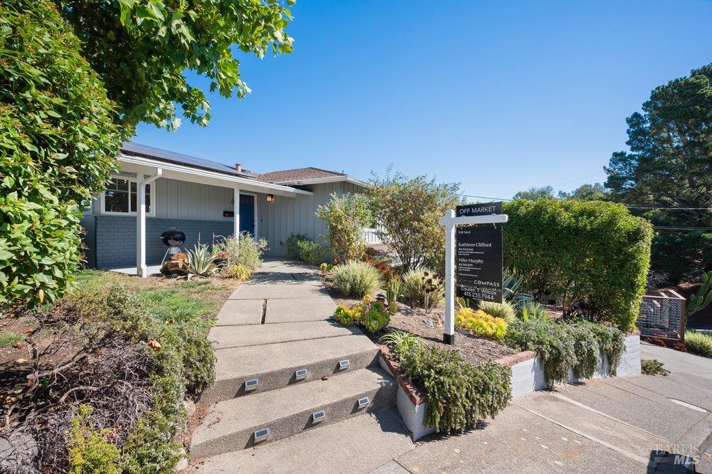 Single-story gray home with a covered porch, landscaped entry, and an OFF MARKET sign.